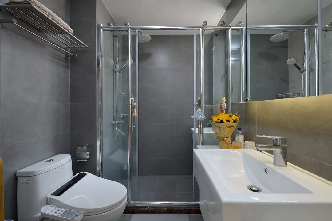 卫生间内做了干湿分离的设计，马桶和洗手台对着摆放，淋浴房靠着窗户。大面积的镜柜可以让卫生间看起来更加宽敞一些。