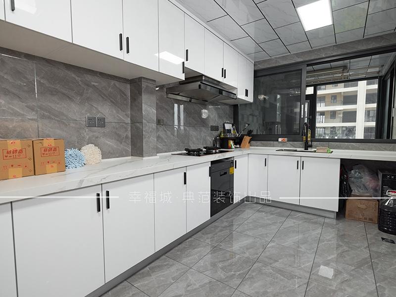 L型厨房，定制的白色橱柜搭配黑色的门把手，时尚大气；用玻璃门将厨房与其他空间隔断，防止烹饪时油烟进入其他区域。